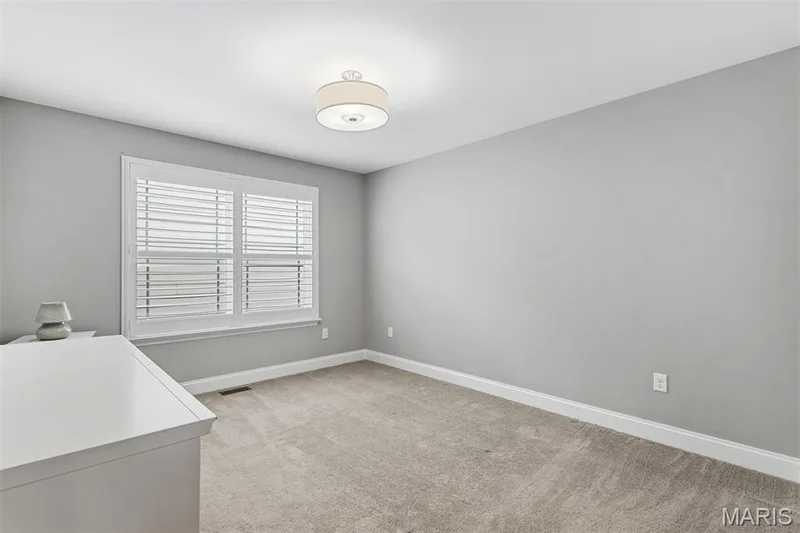 Recessed window with white plantation shutters, neutral-tone walls, and carpet flooring — 17028 Fire Glow Drive, Ballwin, MO 63011
