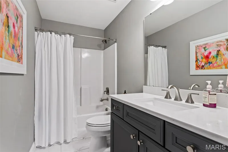 Bathroom featuring a single vanity with dark cabinetry, integrated sink, and brushed nickel fixtures — 17028 Fire Glow Drive, Ballwin, MO 63011