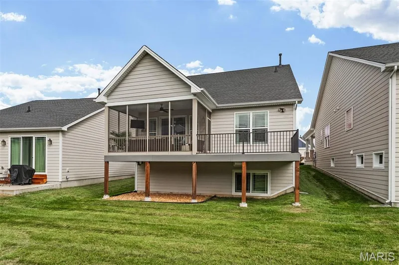 Screened-in porch with a ceiling fan, elevated deck with black metal railing, lower-level windows, and a concrete patio — 17028 Fire Glow Drive, Ballwin, MO 63011