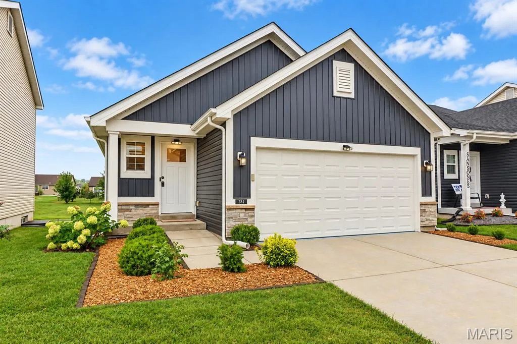 Blue vertical siding exterior with white trim, stone veneer accents, an attached garage, a concrete driveway, and a concrete walkway — 284 Crestfield Court, St Charles, MO 63301