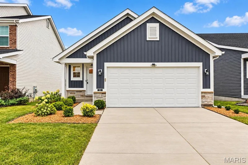 Siding exterior with stone accents, attached garage, concrete driveway, and front landscaping — 284 Crestfield Court, St Charles, MO 63301