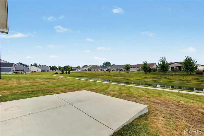 Expansive grassy area featuring a concrete patio, a tranquil pond, and a walking path — 284 Crestfield Court, St Charles, MO 63301