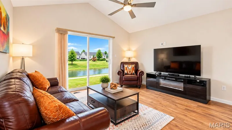 Vaulted ceiling with ceiling fan, wood-finish flooring, and sliding glass door leading to outdoor space — 284 Crestfield Court, St Charles, MO 63301