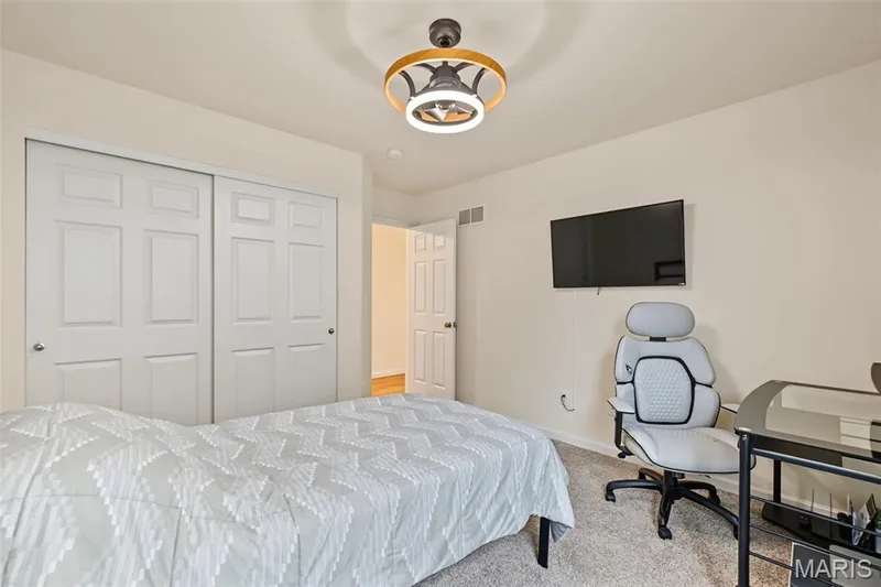 White paneled bi-fold closet doors, wall-mounted television, and a modern ceiling fixture with integrated lighting — 284 Crestfield Court, St Charles, MO 63301