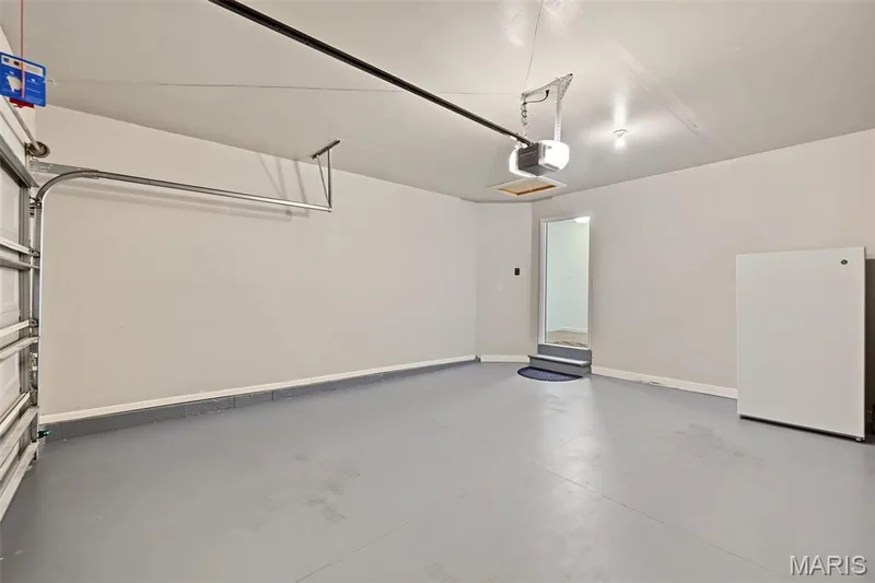 Spacious garage with painted concrete flooring and an automatic garage door opener — 284 Crestfield Court, St Charles, MO 63301