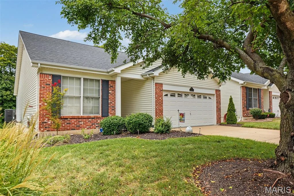 Exterior featuring a two-car garage, brick accents, and a sloped roof — 8 Soenker Circle, St Peters, MO 63376