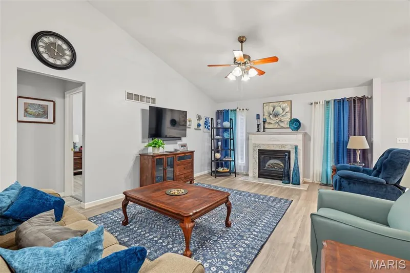 Vaulted ceiling, wood-finish flooring, ceiling fan, fireplace with mantel, and light gray wall paint — 8 Soenker Circle, St Peters, MO 63376