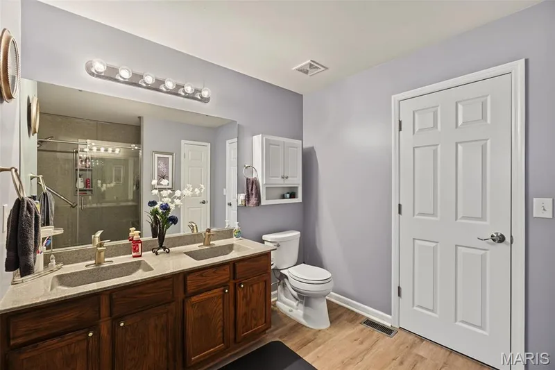 Dual-sink vanity with wood-finish cabinetry and light-toned countertops — 8 Soenker Circle, St Peters, MO 63376