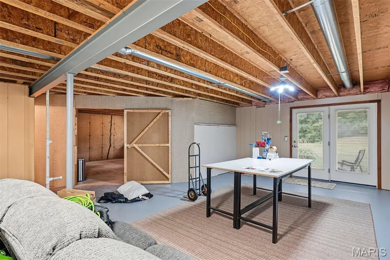 Unfinished basement with exposed ceiling joists, concrete flooring, and French doors — 8 Soenker Circle, St Peters, MO 63376