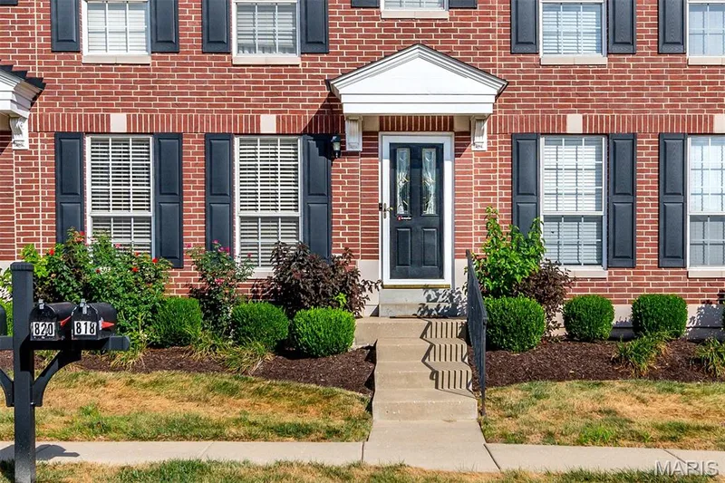 Red brick exterior with white trim details, black window shutters, and a covered entry — 820 Brookmead Drive, O'Fallon, MO 63366