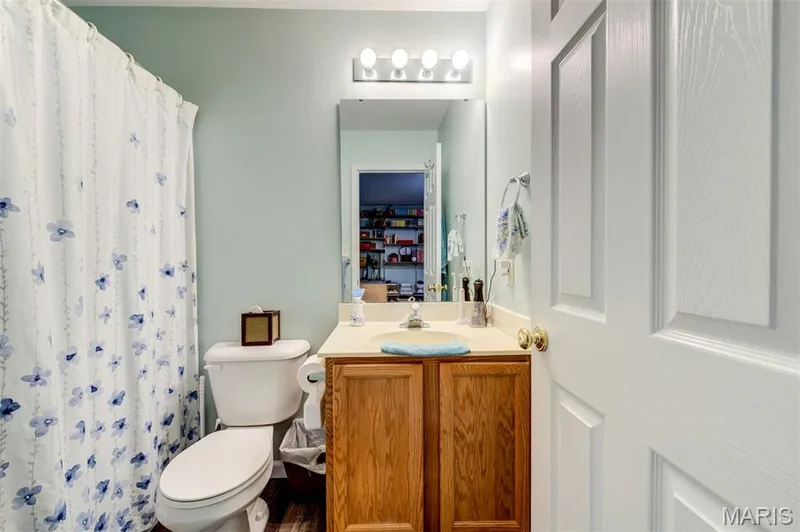 Vanity with wood-finish cabinetry, integrated sink, and light-toned countertop — 820 Brookmead Drive, O'Fallon, MO 63366