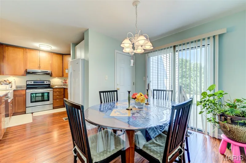 Open-concept kitchen and dining area featuring wood-finish flooring, recessed lighting, and a chandelier — 820 Brookmead Drive, O'Fallon, MO 63366