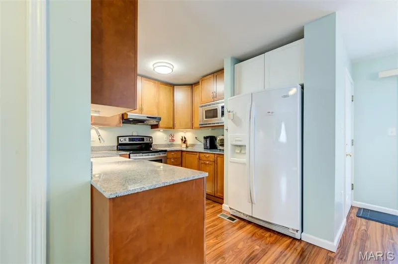 Kitchen featuring wood-finish flooring, granite countertops, wood cabinetry, and recessed lighting — 820 Brookmead Drive, O'Fallon, MO 63366