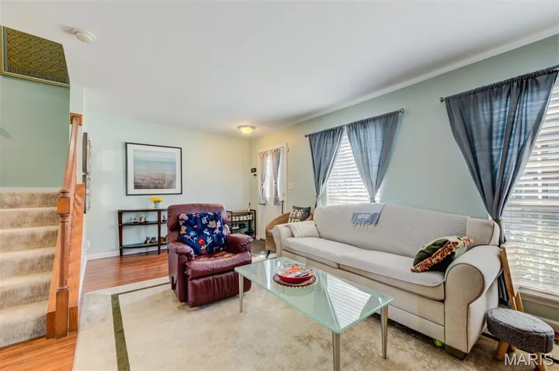 Living area with recessed lighting, wood-finish flooring, and a carpeted staircase with wood handrail — 820 Brookmead Drive, O'Fallon, MO 63366