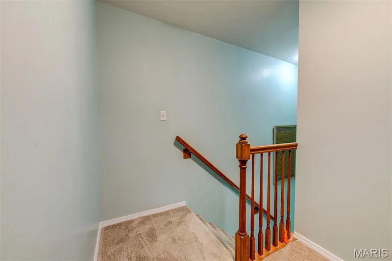 Carpeted staircase with a wood-finish newel post and railings — 820 Brookmead Drive, O'Fallon, MO 63366