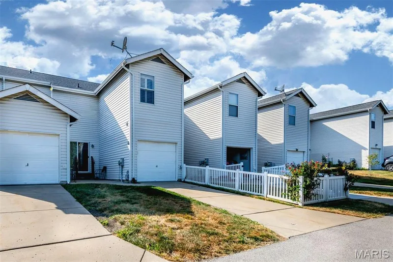 Townhome exterior with light-colored siding, a pitched roof, and an attached garage — 820 Brookmead Drive, O'Fallon, MO 63366
