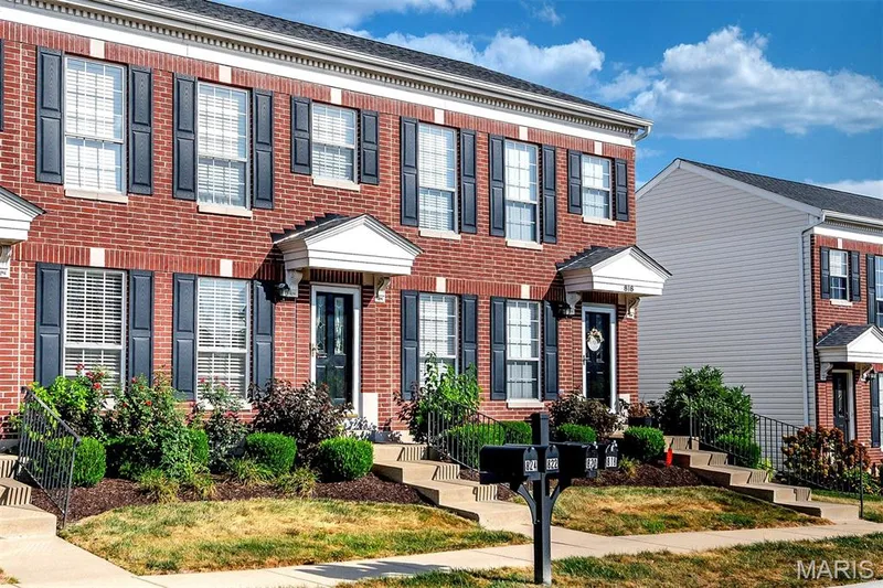 Brick facade with contrasting dark shutters, individual entryways with porticos, and established front landscaping — 820 Brookmead Drive, O'Fallon, MO 63366