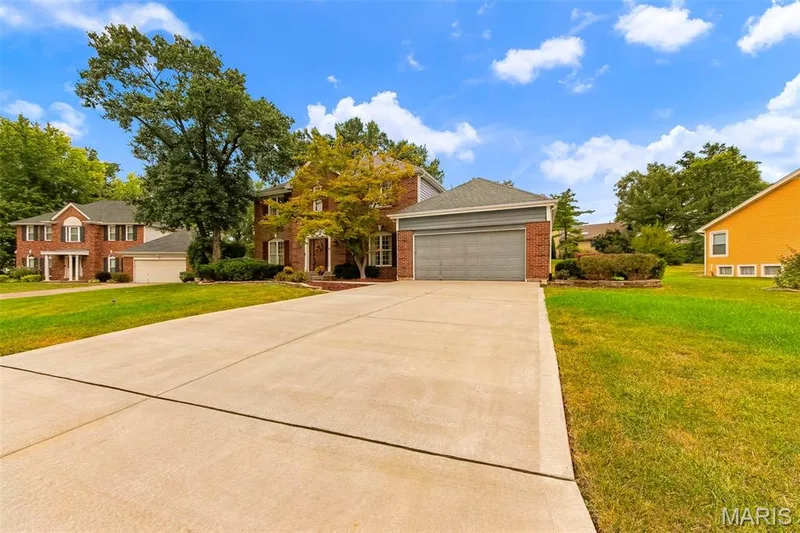 Brick exterior with gray siding accents, attached two-car garage, concrete driveway, front landscaping, and mature trees — 11 Silver Leaf Court, Lake St. Louis, MO 63367