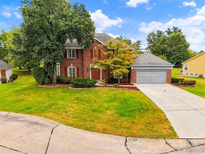 Brick exterior with red shutters, attached garage, concrete driveway, and mature landscaping — 11 Silver Leaf Court, Lake St. Louis, MO 63367