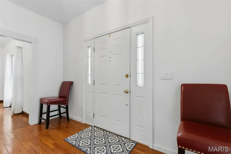 Entryway featuring a white door with sidelights, wood-finish flooring, and white painted walls — 11 Silver Leaf Court, Lake St. Louis, MO 63367