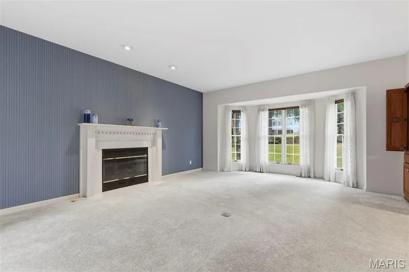 Built-in fireplace with a white mantel, recessed lighting, wall-to-wall carpeting, bay window, and built-in wood cabinetry — 11 Silver Leaf Court, Lake St. Louis, MO 63367
