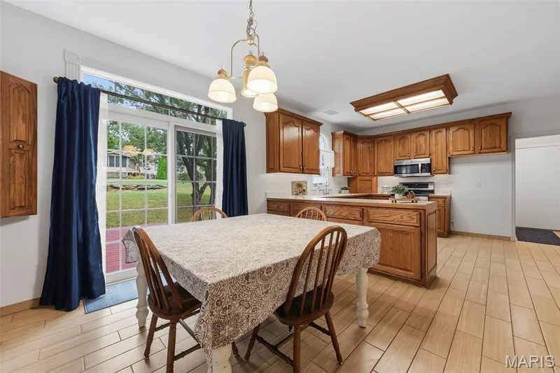 Kitchen with extensive wood cabinetry, L-shaped peninsula with breakfast bar, and tile flooring — 11 Silver Leaf Court, Lake St. Louis, MO 63367