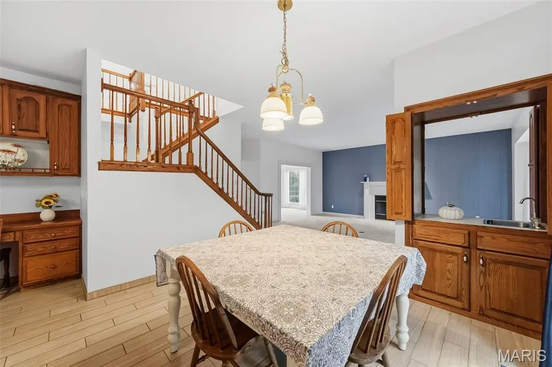 Wood-finish flooring, built-in wooden cabinetry, wooden staircase with balusters, built-in wet bar, and a hanging light fixture — 11 Silver Leaf Court, Lake St. Louis, MO 63367