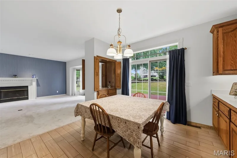 Wood-finish flooring, white countertops, wood cabinetry, and a sliding glass door — 11 Silver Leaf Court, Lake St. Louis, MO 63367