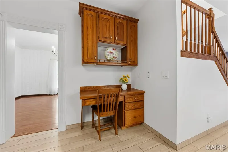 Built-in desk with overhead cabinetry, wood-finish flooring, and white painted walls — 11 Silver Leaf Court, Lake St. Louis, MO 63367