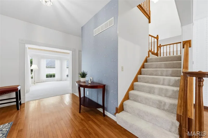 Hardwood flooring, carpeted staircase with wood banister, recessed archway, and overhead lighting fixture — 11 Silver Leaf Court, Lake St. Louis, MO 63367
