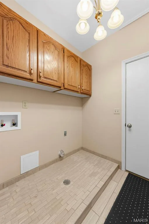 Built-in wood cabinetry with arched panel details, tiled floor with drain, and overhead multi-bulb light fixture — 11 Silver Leaf Court, Lake St. Louis, MO 63367