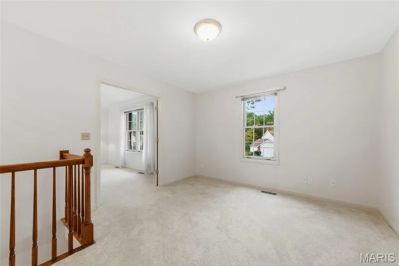 Neutral wall color, light-toned carpeting, wood railing, recessed lighting, and window with natural light — 11 Silver Leaf Court, Lake St. Louis, MO 63367