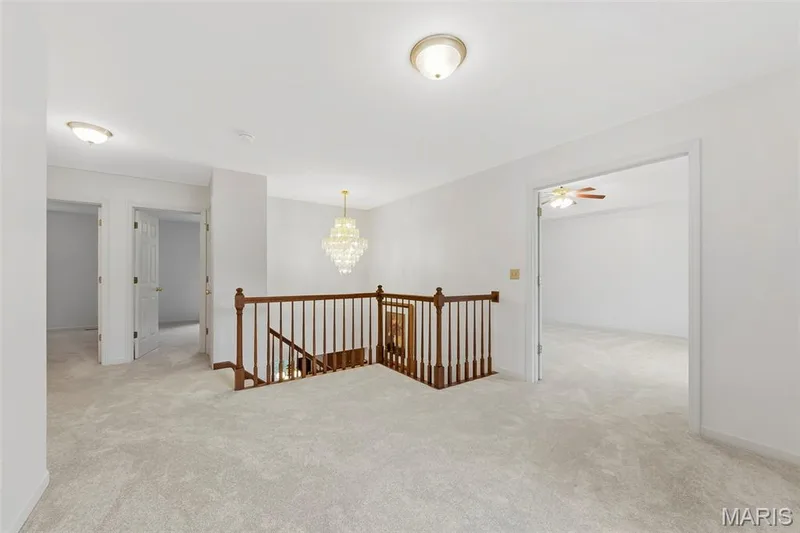 Upper-level landing with plush carpeting, wood railing, and a chandelier — 11 Silver Leaf Court, Lake St. Louis, MO 63367