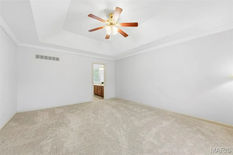 Tray ceiling with crown molding, ceiling fan with integrated lighting, and neutral carpeting — 11 Silver Leaf Court, Lake St. Louis, MO 63367