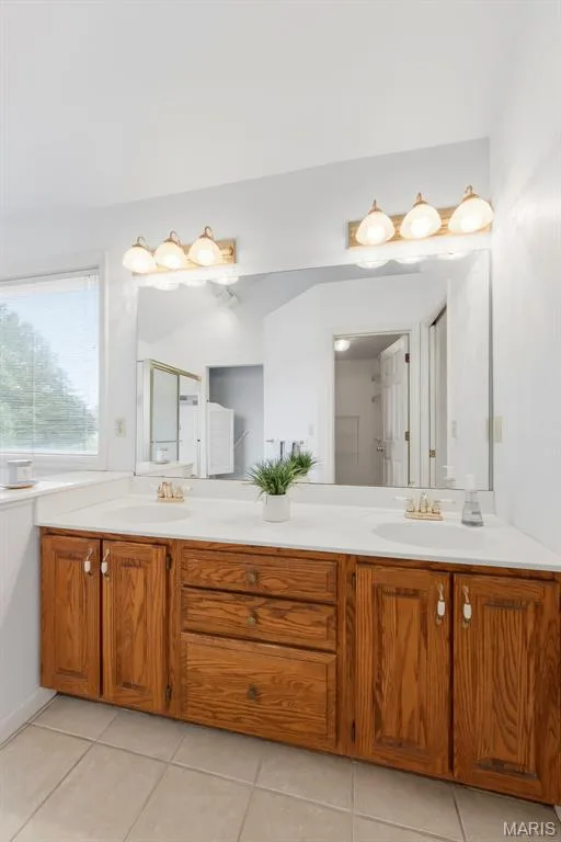 Dual vanity with integrated sinks, wood-finish cabinetry, and a large wall-mounted mirror — 11 Silver Leaf Court, Lake St. Louis, MO 63367