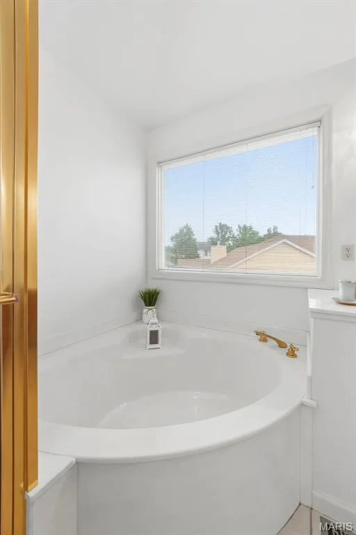 Corner soaking tub featuring brass fixtures and a large window — 11 Silver Leaf Court, Lake St. Louis, MO 63367