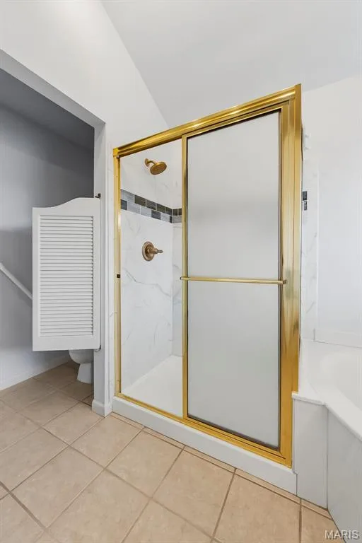 Shower enclosure with a gold-finish frame, frosted and clear glass, and a tiled interior with decorative accent banding — 11 Silver Leaf Court, Lake St. Louis, MO 63367