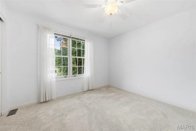 Neutral wall color, light-toned carpeting, multi-pane window, and ceiling fan with integrated lighting — 11 Silver Leaf Court, Lake St. Louis, MO 63367