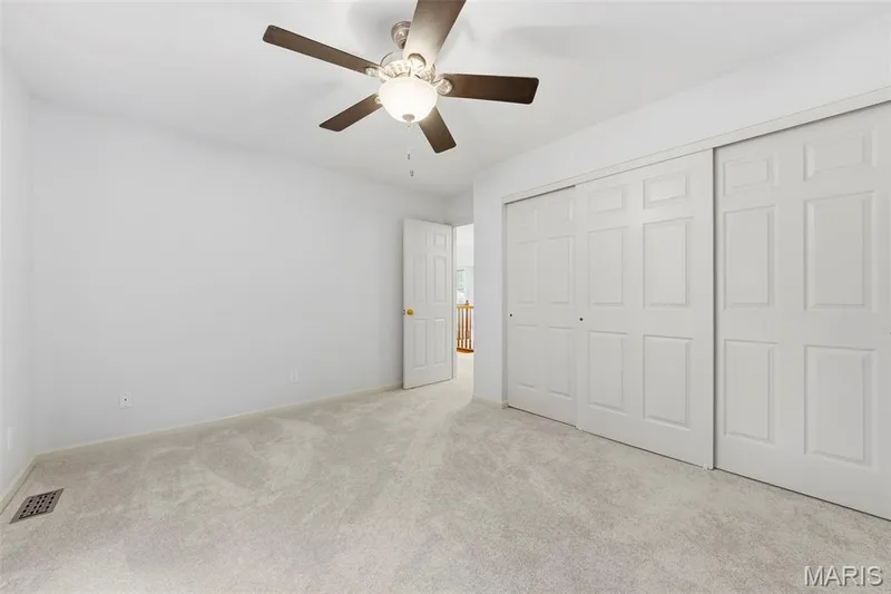 Neutral wall finishes, light-toned carpeting, ceiling fan with integrated lighting, and multiple sliding panel closet doors — 11 Silver Leaf Court, Lake St. Louis, MO 63367