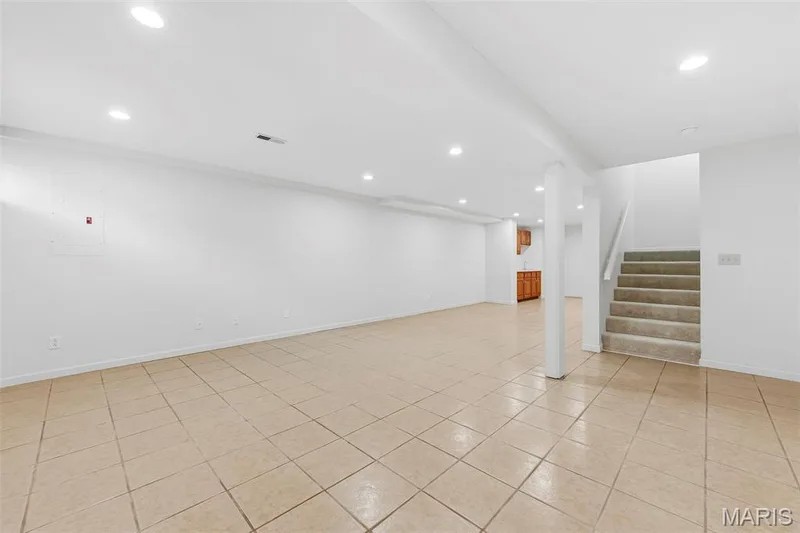 Spacious room featuring tile flooring, recessed lighting, and a staircase with carpeted treads — 11 Silver Leaf Court, Lake St. Louis, MO 63367