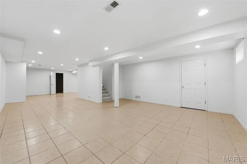 Spacious room featuring tile flooring, recessed lighting, white painted walls, and a white paneled door — 11 Silver Leaf Court, Lake St. Louis, MO 63367