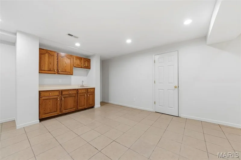Recessed lighting, wood cabinetry, built-in sink, neutral tile flooring, and a paneled interior door — 11 Silver Leaf Court, Lake St. Louis, MO 63367
