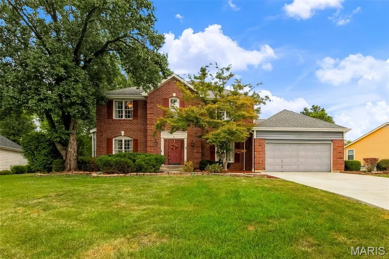 Brick exterior with red shutters, concrete driveway, attached garage, and mature landscaping — 11 Silver Leaf Court, Lake St. Louis, MO 63367