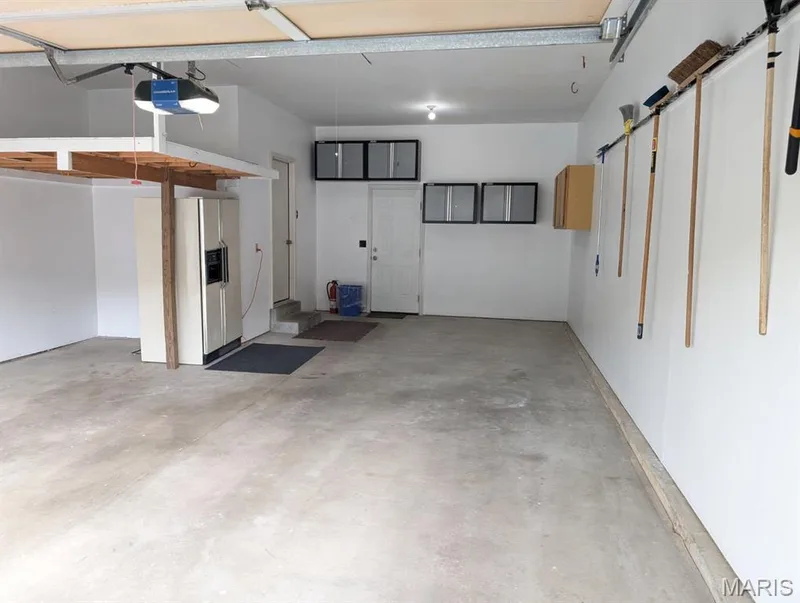 Attached garage with overhead storage, concrete flooring, and built-in wall cabinetry — 11 Silver Leaf Court, Lake St. Louis, MO 63367
