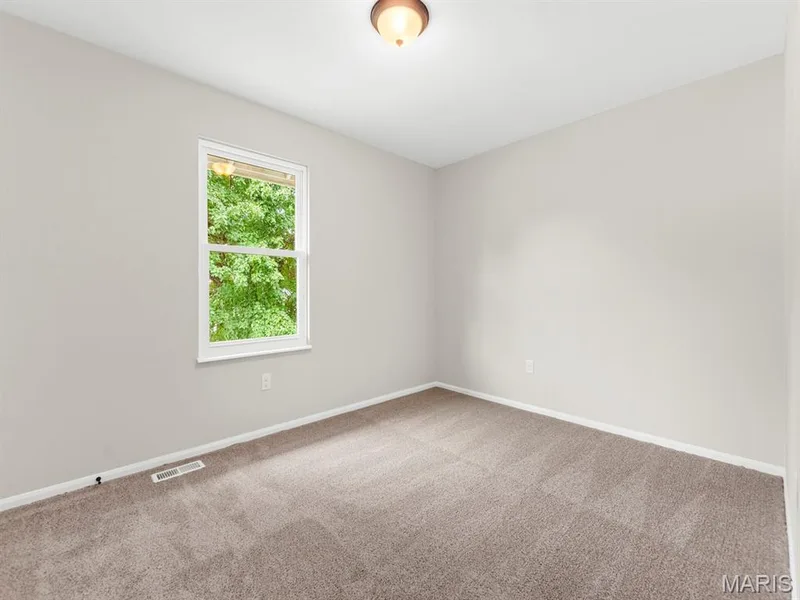 Neutral tone wall paint, light brown carpet flooring, single window, and flush mount ceiling light — 920 Blake Court, St Peters, MO 63376