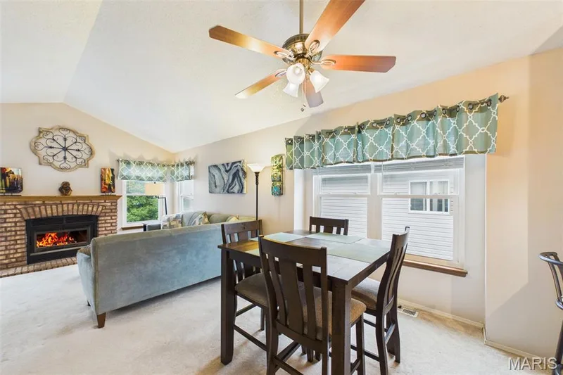 Formal dining area Vaulted ceiling with ceiling fan, brick-surround fireplace, and multiple windows — 2931 Plum Leaf Circle, St Peters, MO 63303