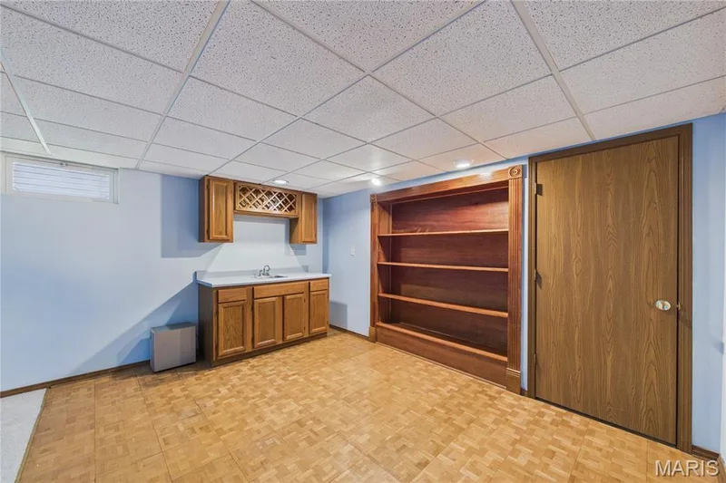 Built-in shelving, wood-finish flooring, drop ceiling, built-in cabinetry, and window — 2931 Plum Leaf Circle, St Peters, MO 63303