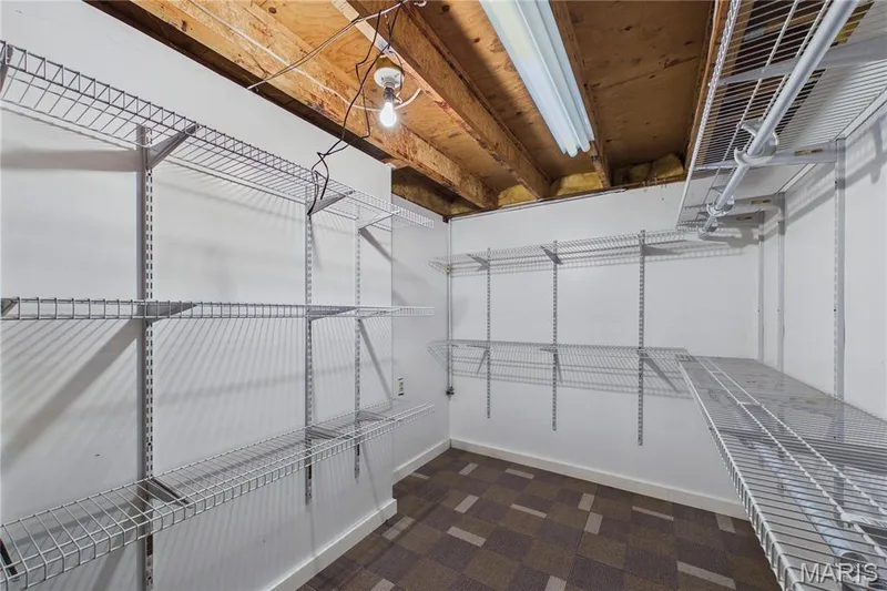 Potential additional closet or storage area. White wire shelving system, fluorescent lighting, and patterned carpet flooring — 2931 Plum Leaf Circle, St Peters, MO 63303