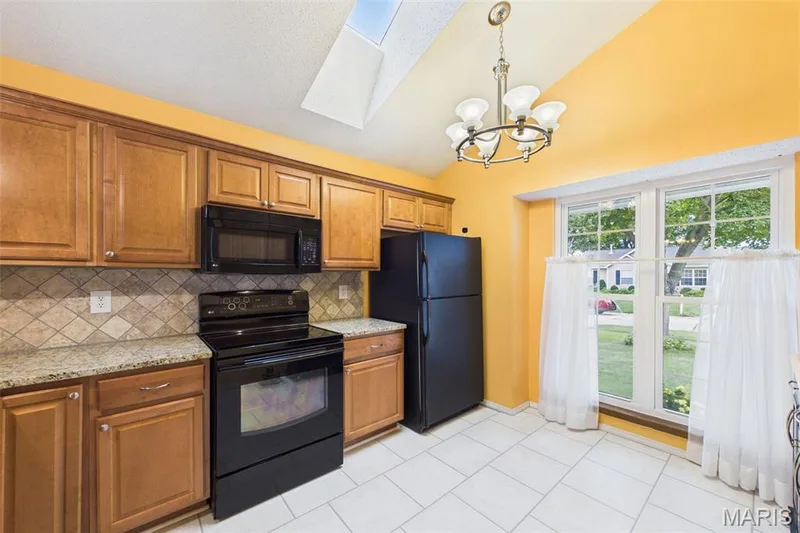Bright airy Kitchen featuring wood-finish cabinetry, black appliances, luxury plank flooring w/a skylight — 2931 Plum Leaf Circle, St Peters, MO 63303