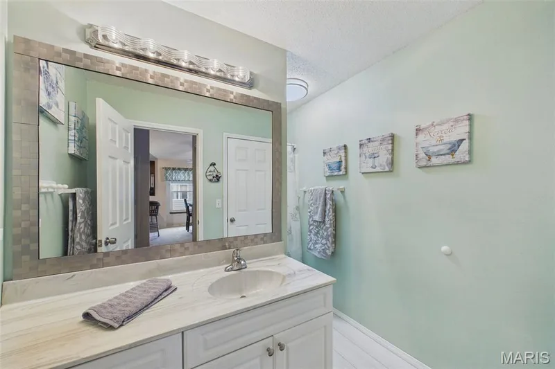 Vanity with a single basin sink, light-toned countertop, and white cabinetry including a full shower and tub combo — 2931 Plum Leaf Circle, St Peters, MO 63303